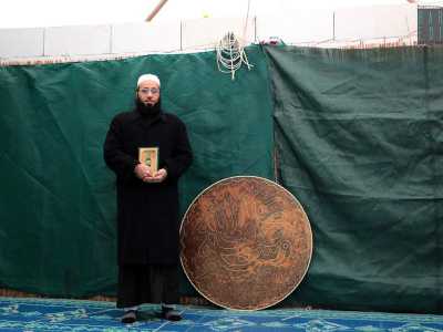 Ci colpisce un scultura in legno tondeggiante che decora la sala, accanto a cui posa per una foto l�imam Swandy Ghazy, un uomo con una lunga barba vestito con una tunica nera detta giarabia. In mano ha il Corano. 
